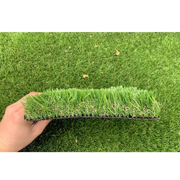 تکه ای از چمن مصنوعی توسط دست انسان نگه داشته شده